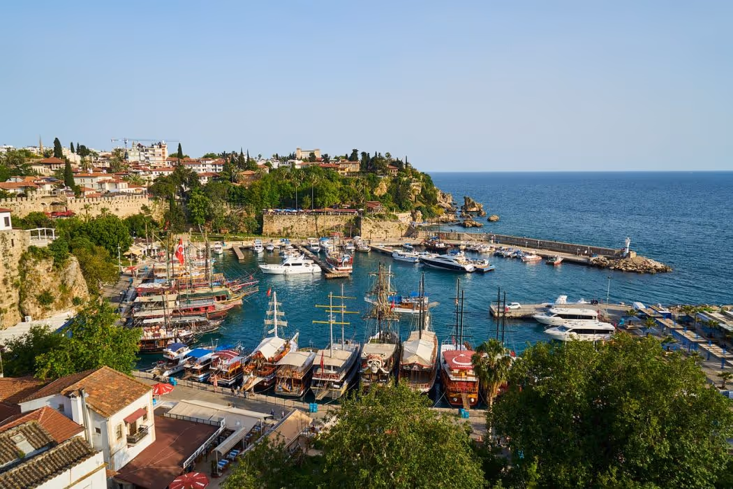 Afgemeerde boten in de haven van Antalya met de rotsen van de oude stad erachter