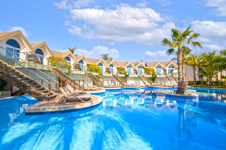 Zwembad met palmen en villa's van Long Beach Resort in Türkler