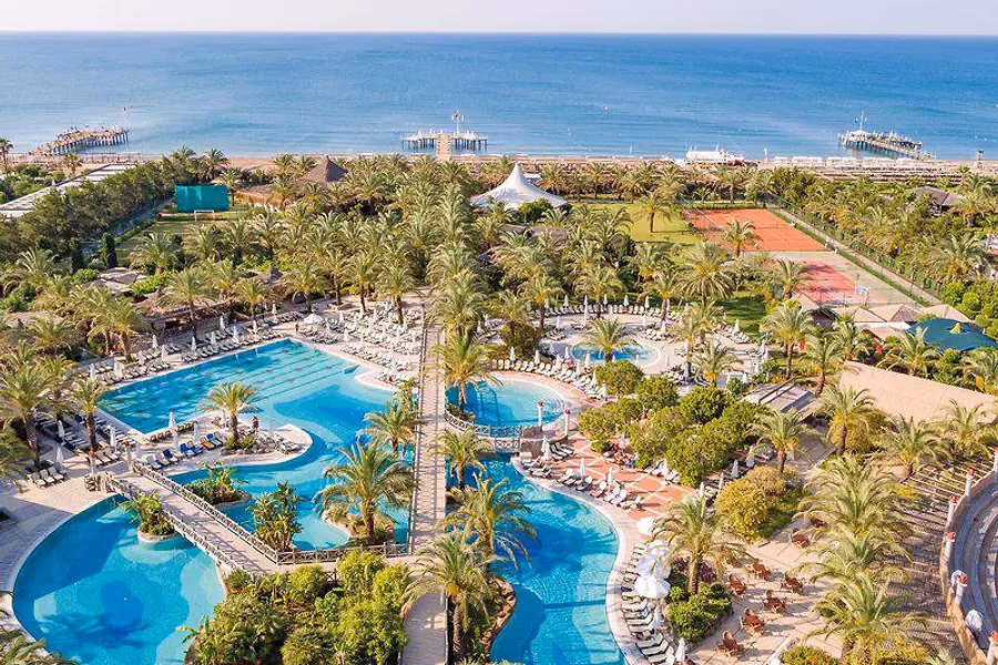 Zwembaden en palmen van Royal Wings Hotel in Lara, met de zee erachter