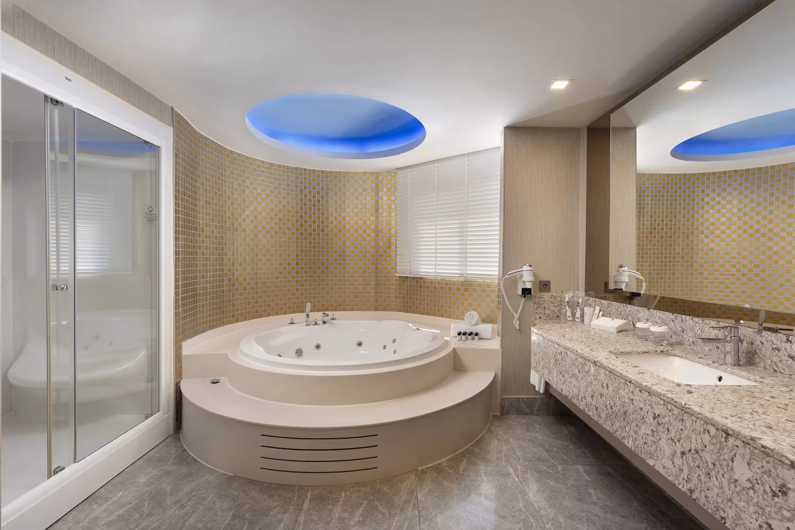 Badkamer met een rond bubbelbad onder een blauw verlicht plafond en een wastafel bij Royal Seginus in Lara