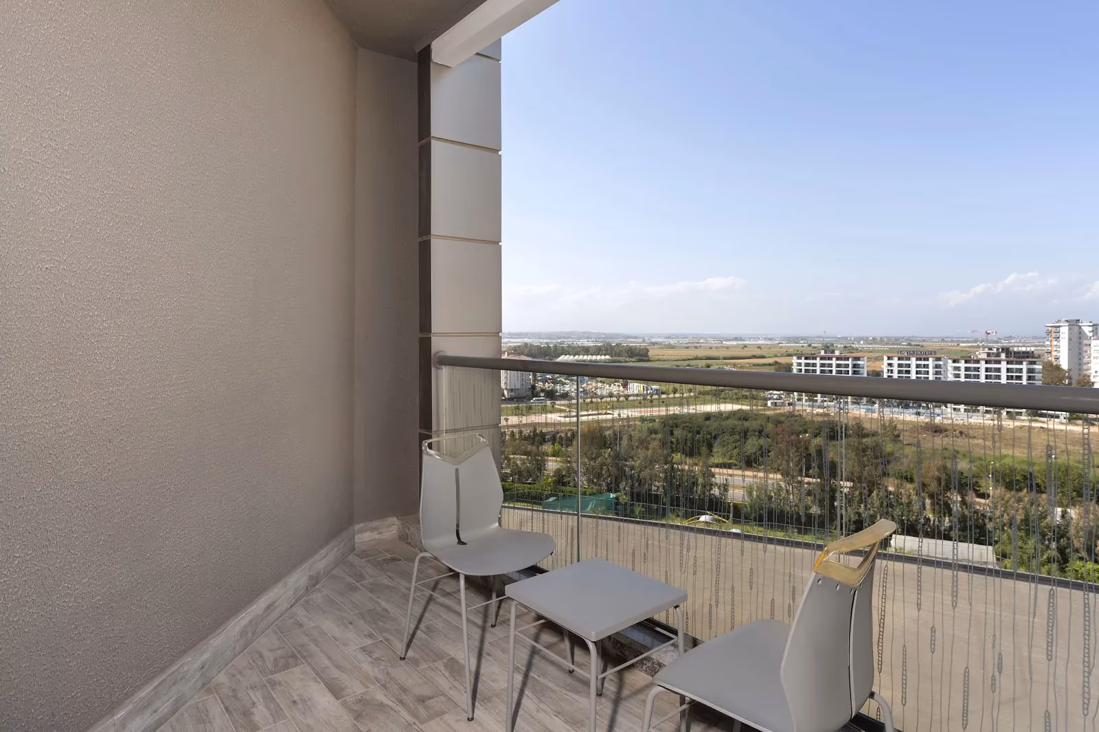 Balkon met twee stoelen en een tafel met uitzicht op groen en gebouwen bij Royal Seginus in Lara