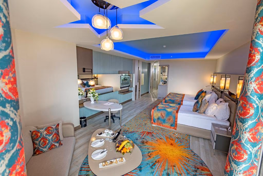 Familiekamer met een tweepersoonsbed, een zithoek met kleurige kussens en een blauw verlicht plafond bij Royal Seginus in Lara