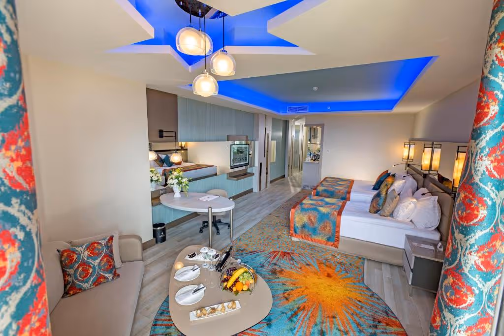 Familiekamer met een tweepersoonsbed, een zithoek met kleurige kussens en een blauw verlicht plafond bij Royal Seginus in Lara