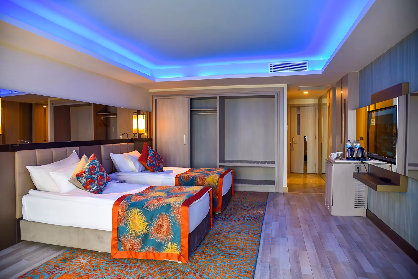 Duplexkamer met twee eenpersoonsbedden, een tv, een bureau en een blauw verlicht plafond bij Royal Seginus in Lara