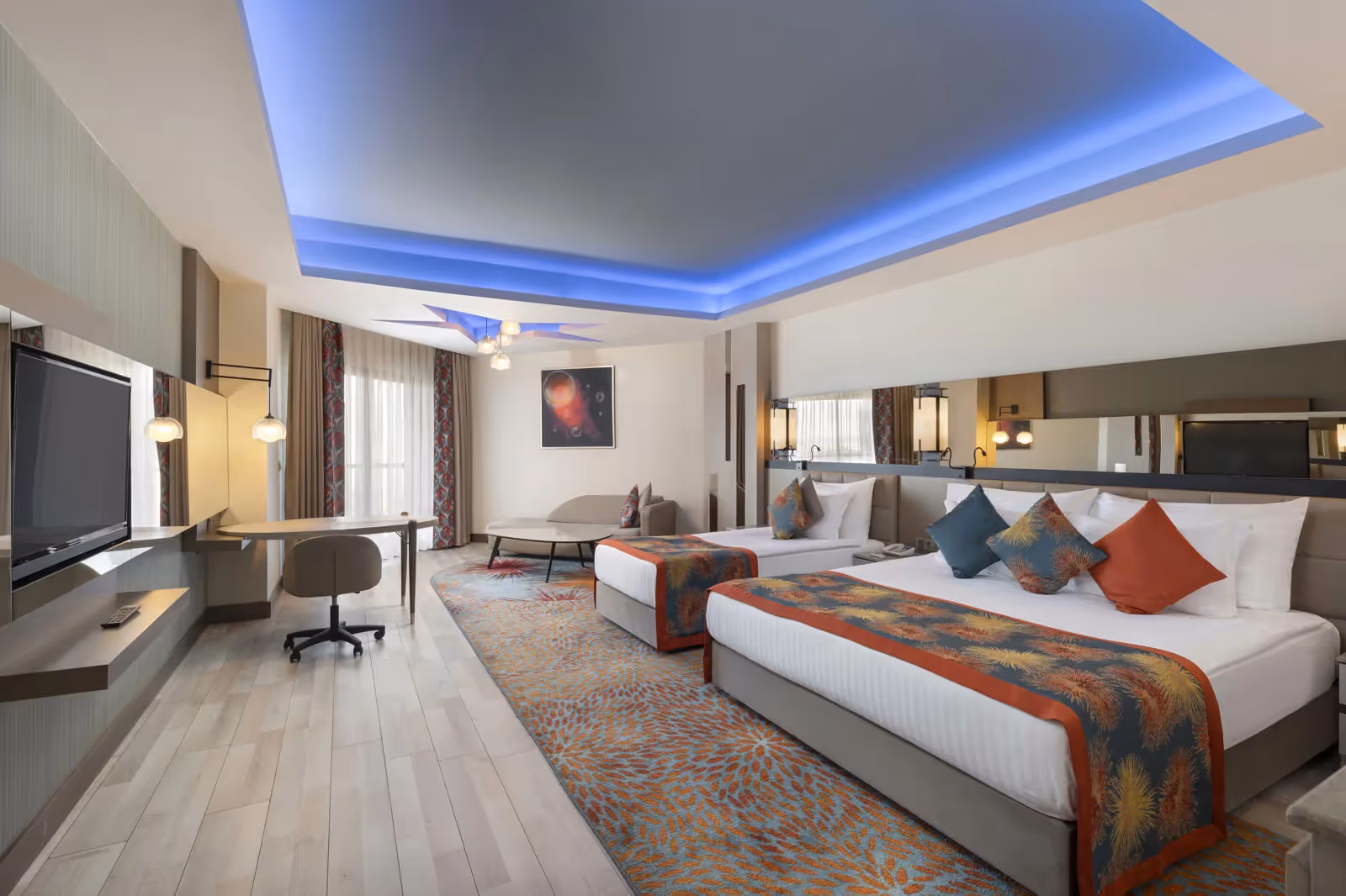 Kamer met twee bedden, een tv, een bureau en een blauw verlicht plafond bij Royal Seginus in Lara