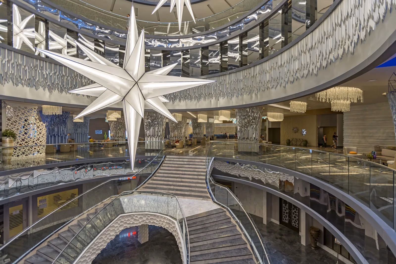 De lobby met een atrium, een grote stervormige kroonluchter en trappen bij Royal Seginus in Lara