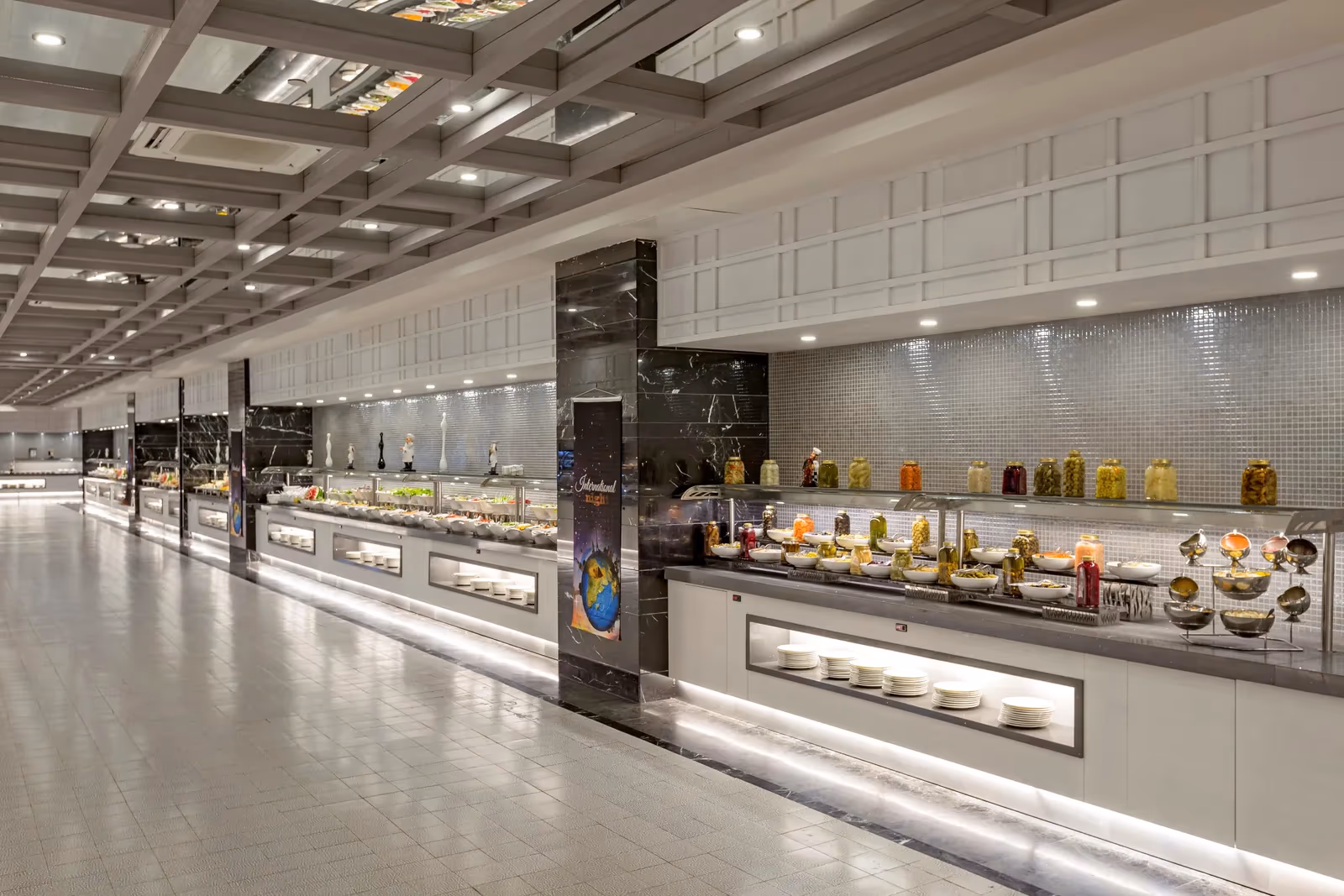 Lange buffetzaal met meerdere buffetlijnen onder een lichte plafondconstructie bij Royal Seginus in Lara