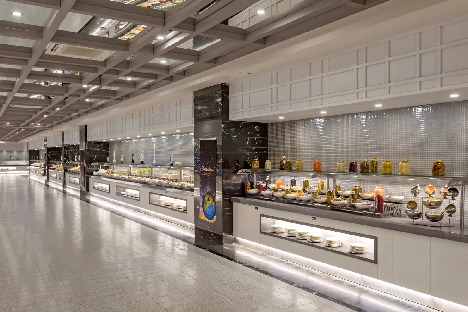 Lange buffetzaal met meerdere buffetlijnen onder een lichte plafondconstructie bij Royal Seginus in Lara