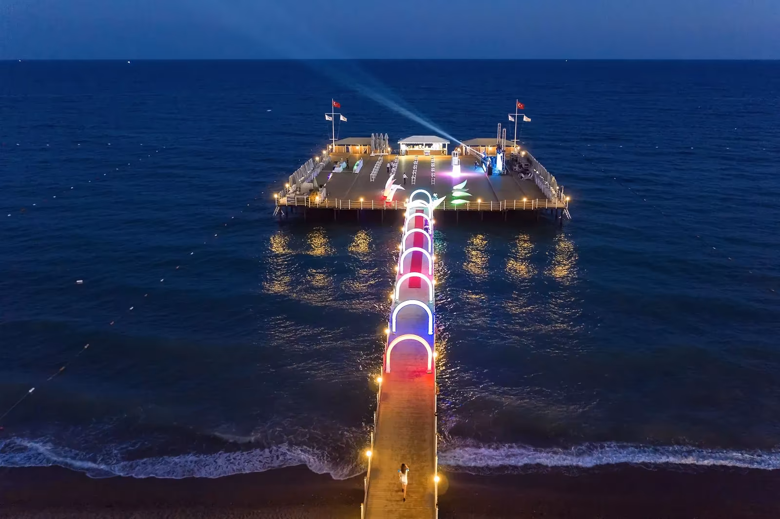 Luchtfoto van de verlichte pier in zee in de avond bij Royal Seginus in Lara